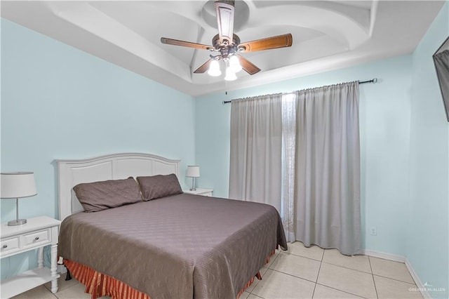 bedroom featuring a raised ceiling, light tile patterned flooring, ceiling fan, and baseboards