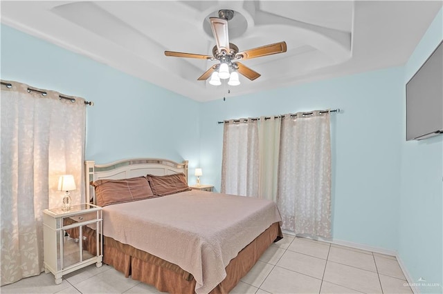 bedroom featuring a tray ceiling, ceiling fan, baseboards, and tile patterned floors