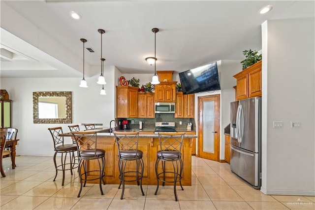 kitchen with light tile patterned floors, decorative backsplash, a breakfast bar, a peninsula, and stainless steel appliances