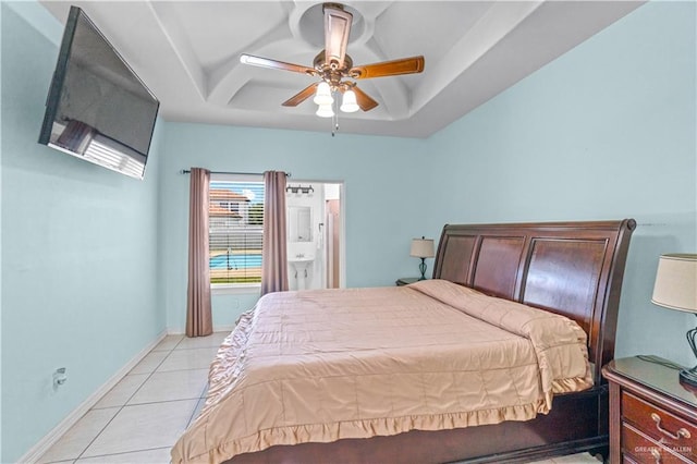 bedroom featuring light tile patterned floors, baseboards, a raised ceiling, and a ceiling fan