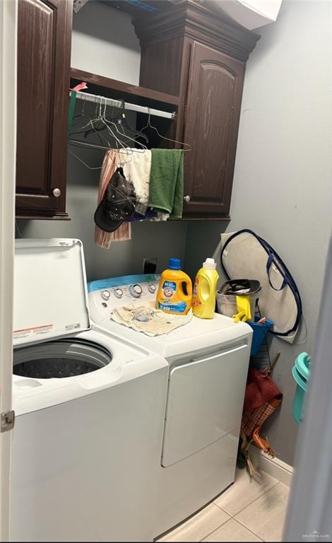 clothes washing area with light tile patterned flooring, cabinets, and washing machine and dryer