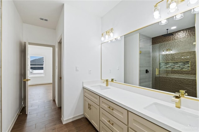 bathroom with a stall shower, wood tiled floor, visible vents, and a sink