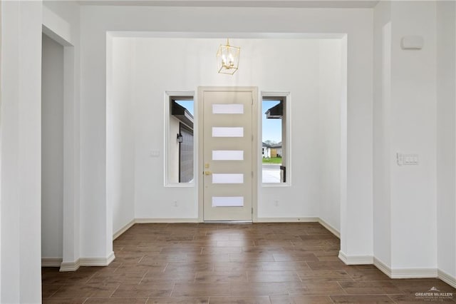 foyer entrance with an inviting chandelier, wood finished floors, and baseboards