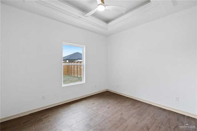 unfurnished room featuring a ceiling fan, a raised ceiling, baseboards, and wood finished floors