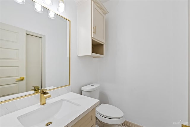 half bathroom featuring toilet, baseboards, and vanity