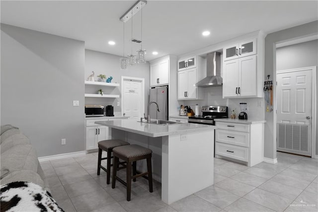 kitchen featuring visible vents, a kitchen breakfast bar, stainless steel appliances, wall chimney range hood, and a sink