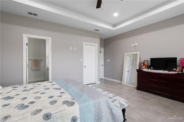 bedroom with ceiling fan, connected bathroom, visible vents, baseboards, and a raised ceiling