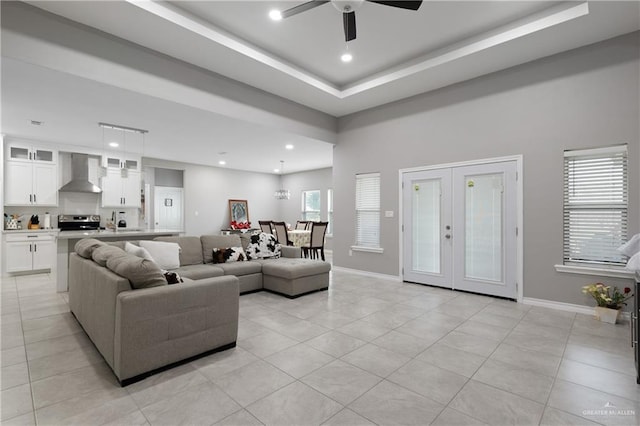 living room with a tray ceiling, light tile patterned flooring, recessed lighting, and baseboards