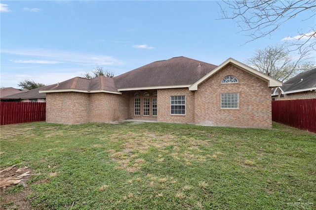 back of house featuring a fenced backyard, a shingled roof, french doors, a lawn, and brick siding