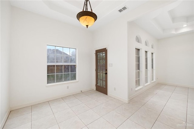 unfurnished room with light tile patterned floors, visible vents, a raised ceiling, and baseboards