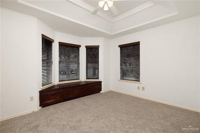 unfurnished room with a tray ceiling, ceiling fan, and light colored carpet