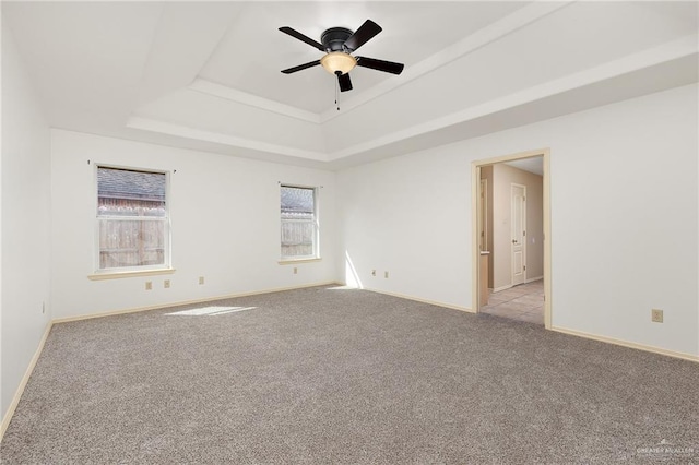 carpeted spare room featuring a raised ceiling and ceiling fan