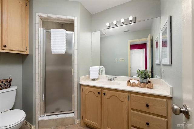 bathroom featuring tile patterned flooring, vanity, toilet, and a shower with door