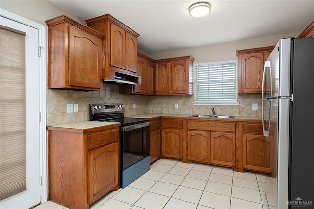 kitchen featuring appliances with stainless steel finishes, sink, decorative backsplash, and light tile patterned floors