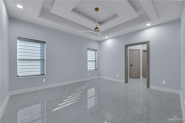 spare room featuring a raised ceiling and ceiling fan