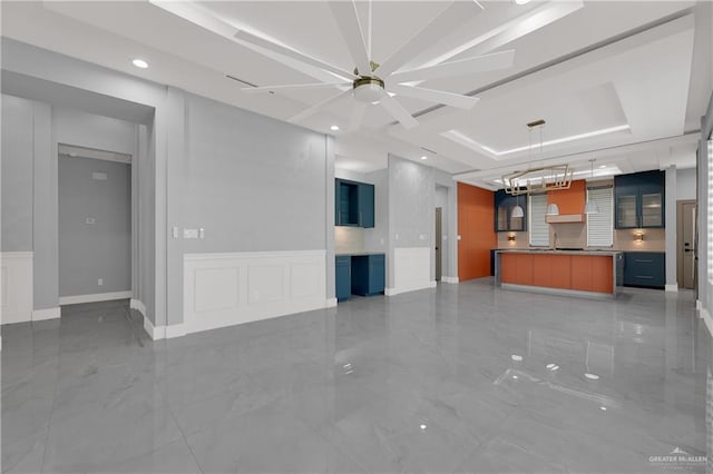 unfurnished living room with a raised ceiling, ceiling fan, and sink