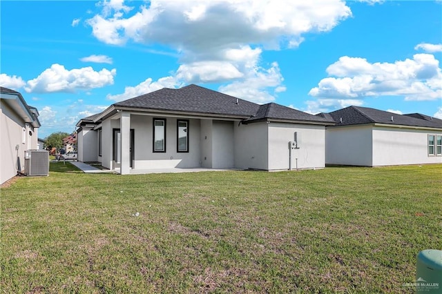 back of property with central AC unit, a patio area, and a lawn