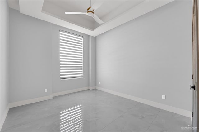 spare room with ceiling fan and a tray ceiling