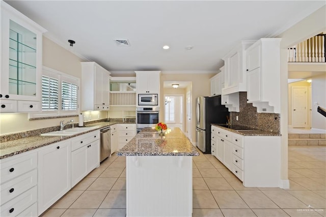 5501 N 1st Ln, Mcallen, TX 78504 - kitchen with appliances with stainless steel finishes, ornamental molding, white cabinets, light stone counters, and a center island