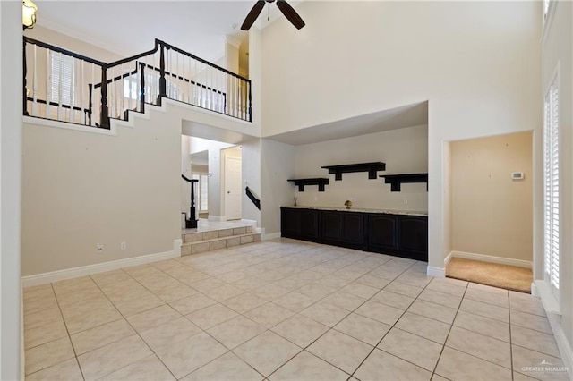 5501 N 1st Ln, Mcallen, TX 78504 - unfurnished living room featuring a towering ceiling, stairway, light tile patterned floors, ceiling fan, and plenty of natural light