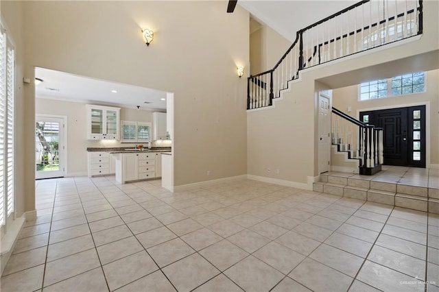 5501 N 1st Ln, Mcallen, TX 78504 - unfurnished living room featuring a towering ceiling, stairs, light tile patterned floors, and baseboards