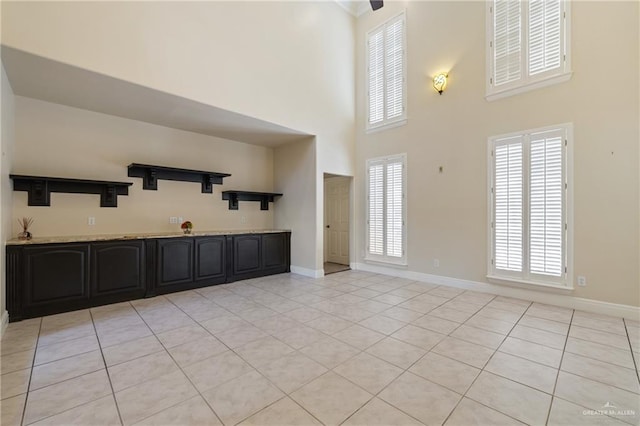 5501 N 1st Ln, Mcallen, TX 78504 - unfurnished living room featuring a towering ceiling, light tile patterned floors, and baseboards