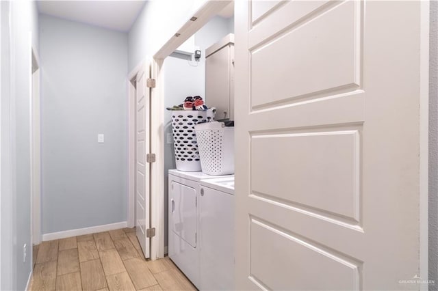 clothes washing area with separate washer and dryer and baseboards