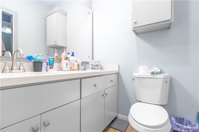 bathroom with toilet, baseboards, and vanity