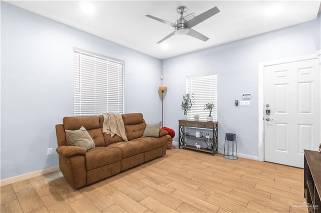living area featuring ceiling fan, baseboards, and light wood-style floors