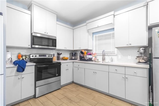 kitchen with light countertops, stainless steel appliances, a sink, and backsplash