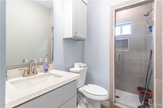 bathroom with vanity, a shower stall, and toilet