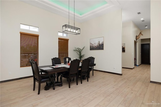 dining space with light wood-type flooring and a high ceiling