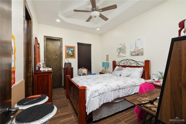 bedroom with a raised ceiling, ceiling fan, and dark wood-type flooring