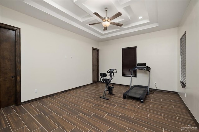 workout area featuring a raised ceiling, ceiling fan, and dark hardwood / wood-style flooring