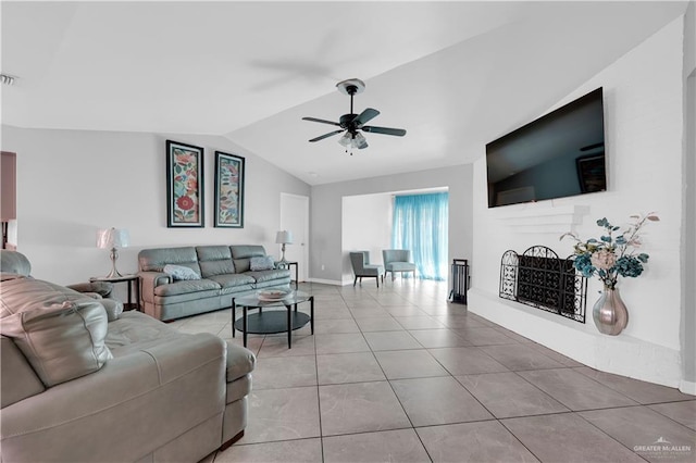 living room with visible vents, a fireplace with raised hearth, a ceiling fan, light tile patterned floors, and vaulted ceiling