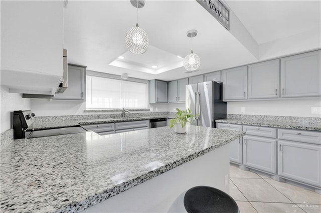 kitchen with light stone counters, gray cabinets, stainless steel appliances, and a raised ceiling