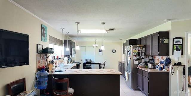 2219 Ella Ave, Harlingen, TX 78550 - kitchen with stainless steel appliances, crown molding, hanging light fixtures, light tile patterned flooring, and light countertops