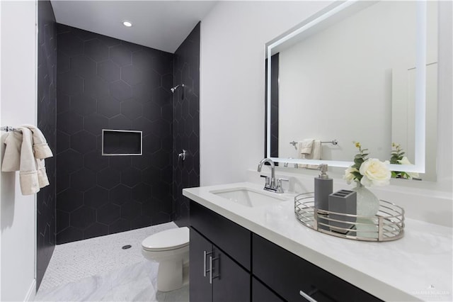 bathroom with tiled shower, vanity, and toilet