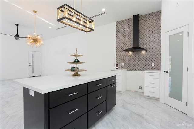 kitchen with white cabinetry, a center island, wall chimney exhaust hood, pendant lighting, and decorative backsplash