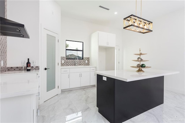 kitchen with a center island, white cabinets, sink, tasteful backsplash, and decorative light fixtures