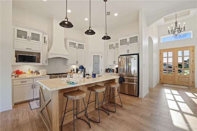 13801 N 37th St, Mcallen, TX 78504 - kitchen with appliances with stainless steel finishes, arched walkways, a high ceiling, a kitchen island with sink, and white cabinetry