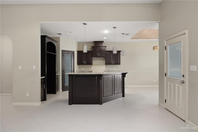 kitchen featuring recessed lighting, baseboards, an island with sink, and hanging light fixtures