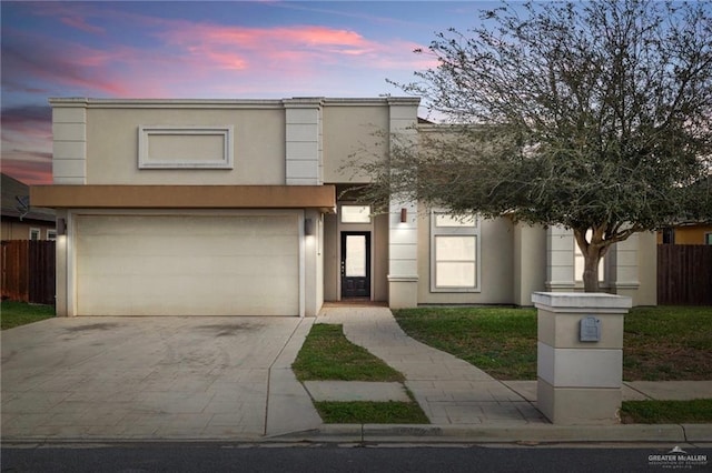 view of front facade with stucco siding, a garage, concrete driveway, and fence