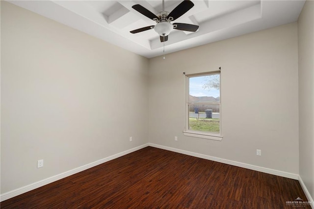 empty room featuring ceiling fan, a tray ceiling, baseboards, and dark wood-style floors