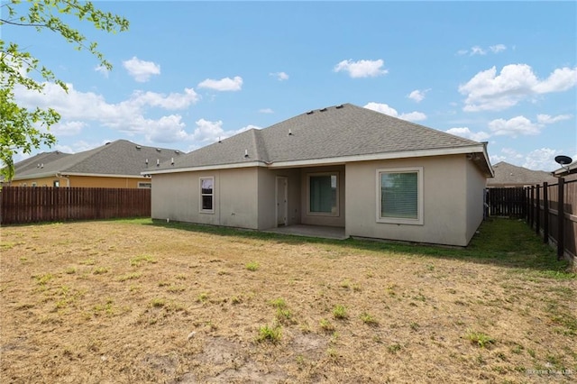 rear view of property with stucco siding, a lawn, a fenced backyard, and a shingled roof