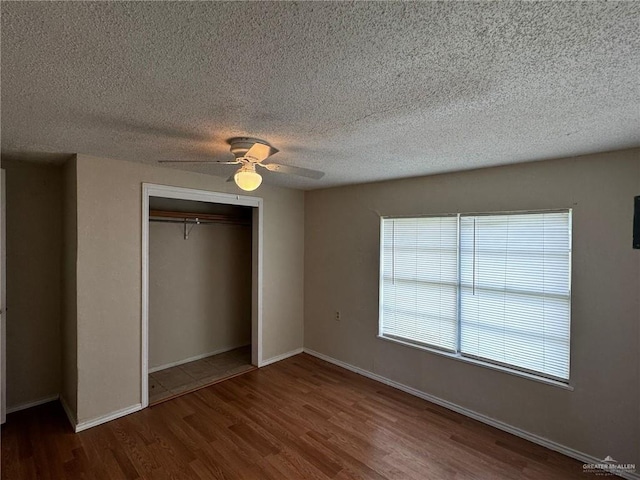 unfurnished bedroom with a textured ceiling, a closet, hardwood / wood-style flooring, and ceiling fan