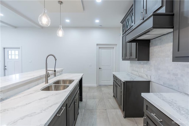 kitchen featuring light stone countertops, decorative light fixtures, tasteful backsplash, and sink