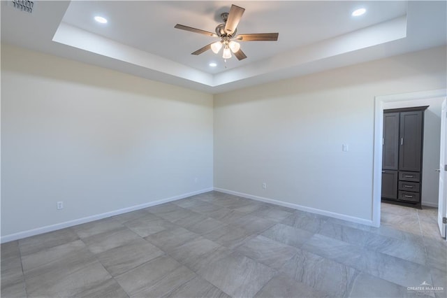 unfurnished room with a raised ceiling and ceiling fan