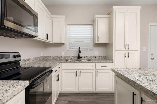 kitchen featuring white cabinets, stainless steel microwave, a sink, and electric range oven