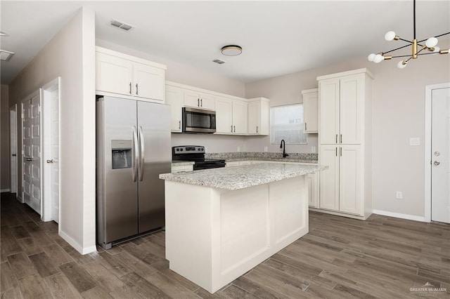 kitchen with stainless steel appliances, a kitchen island, white cabinetry, visible vents, and pendant lighting